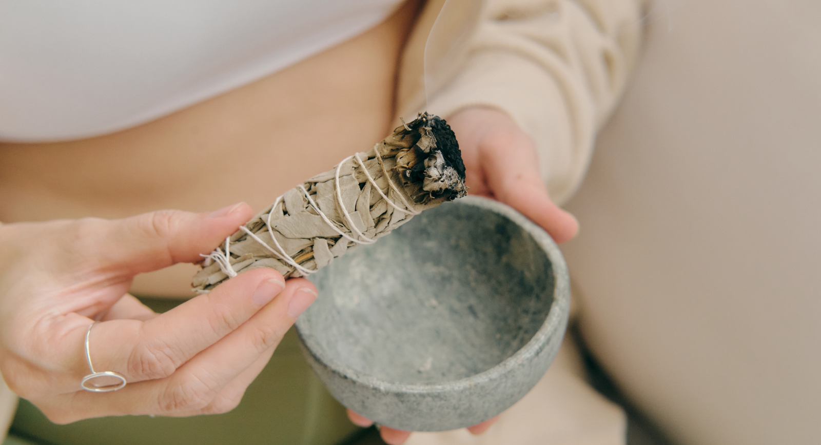 Photo - Woman burning sage while holding a bowl in her hand