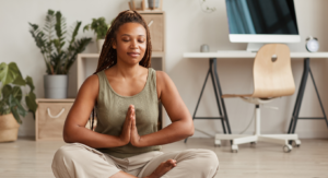 photo - black woman meditating in lotus position with hands in front of her heart